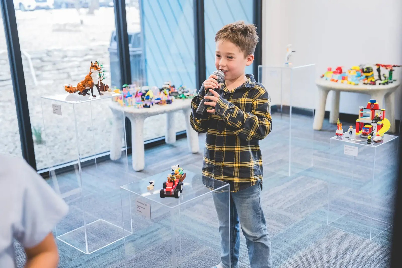 Menino apresenta seu projeto de Lego ao microfone, numa oficina da Alpha School