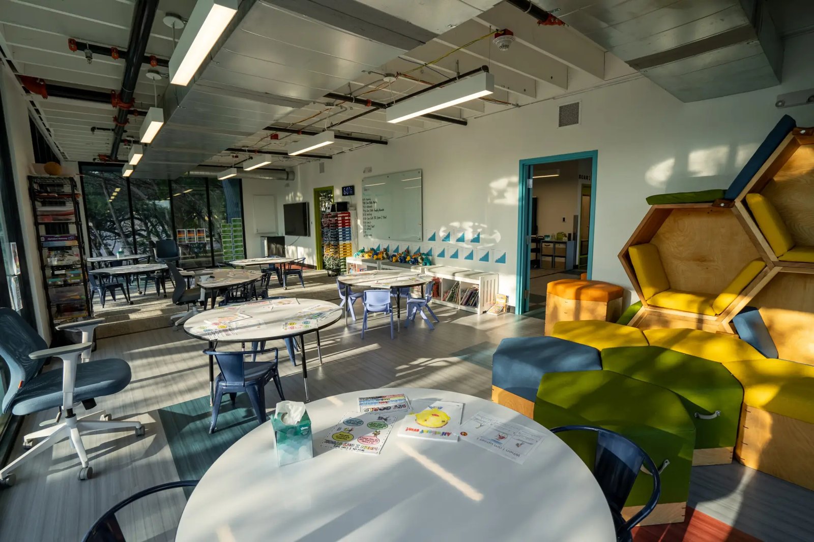 Sala ampla do campus da Alpha School em Austin, com mesas redondas, poltronas e nichos de leitura